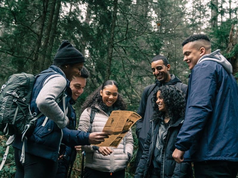 Friends exploring a forest trail with a map
