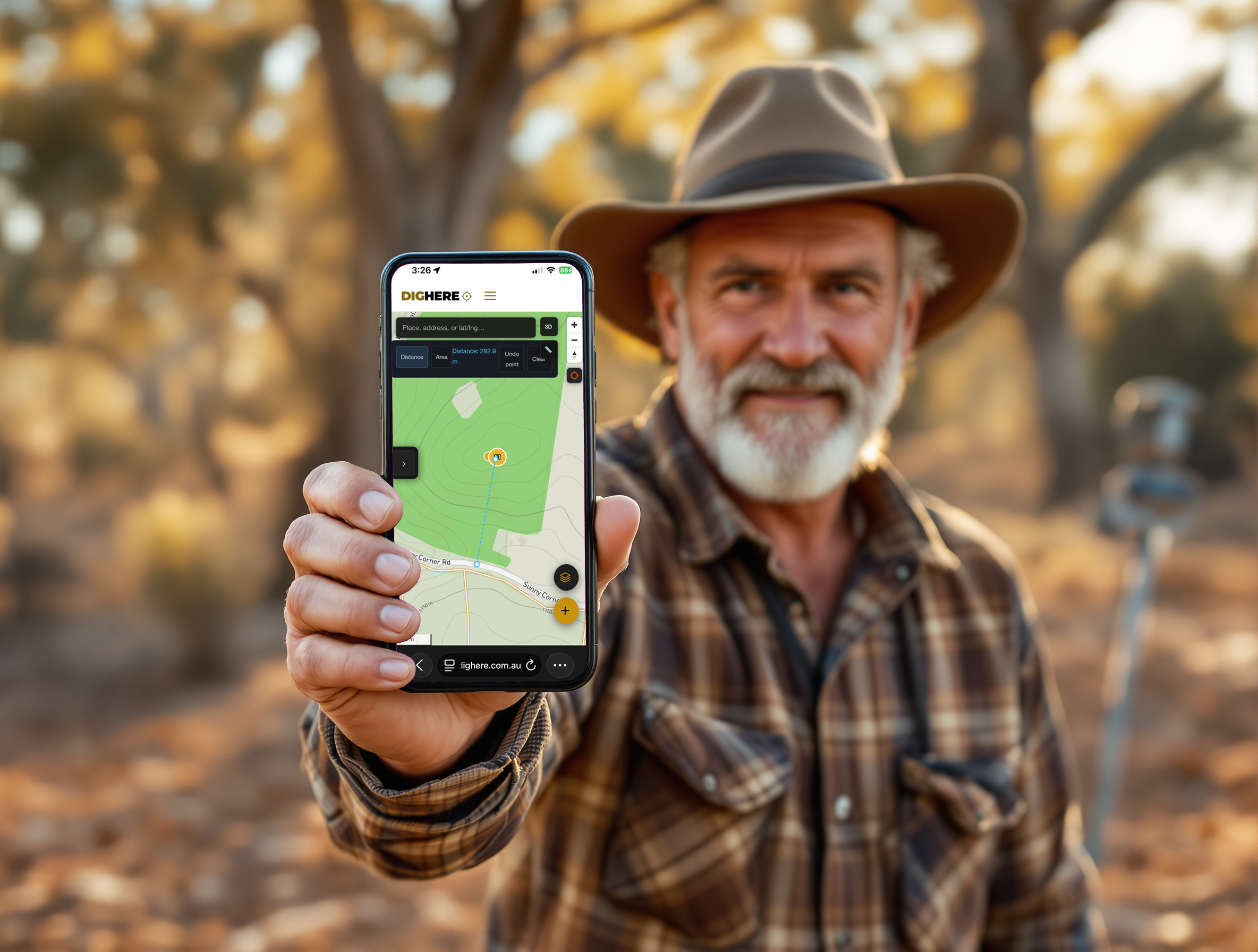 A prospector in golden-hour Australian bush holding up an iPhone running Dig Here, measuring 292 metres from Sunny Corner Road to a gold pin